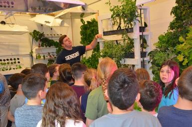 Senior student explains hydroponics to third graders.