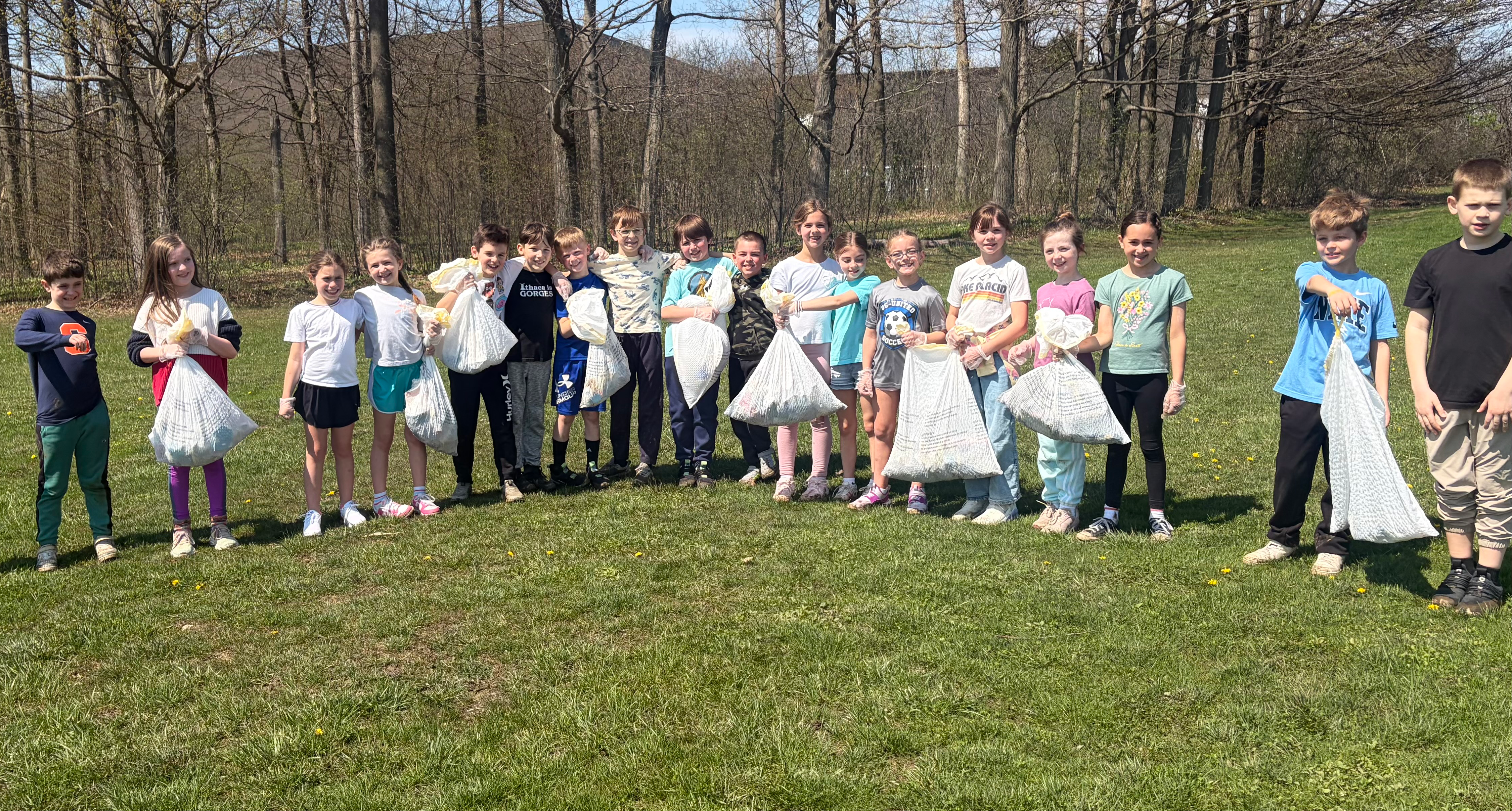 Students hold trash bags after cleaning up for Earth Day