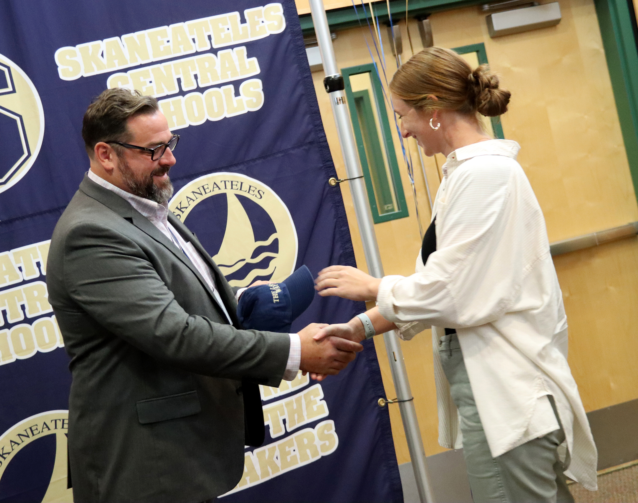 Superintendent Eric Knuth hands a hat to new hire Emma Solomon